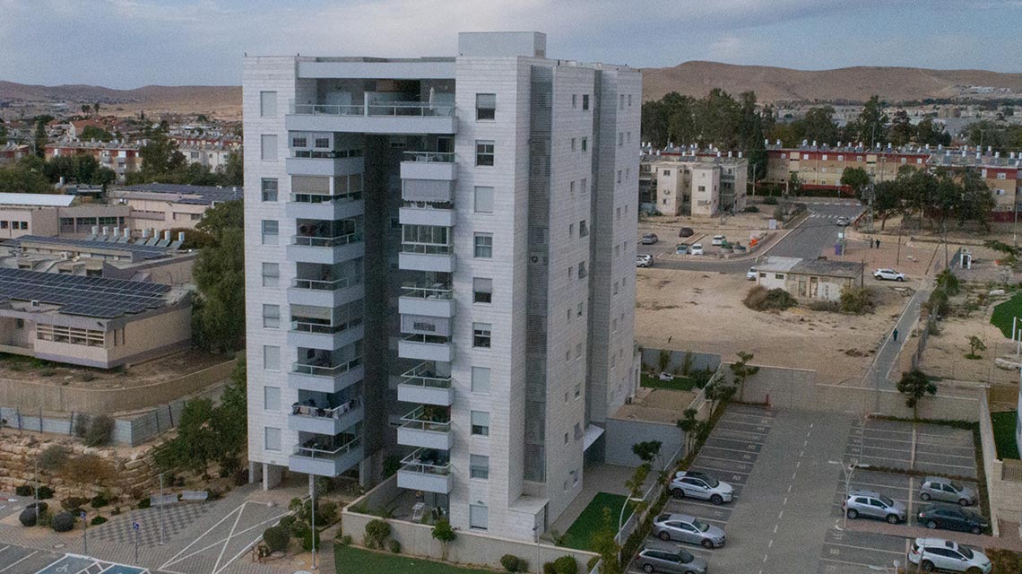 מבט לחזית רחוקה של בניין מגורים בן 11 קומות בדימונה